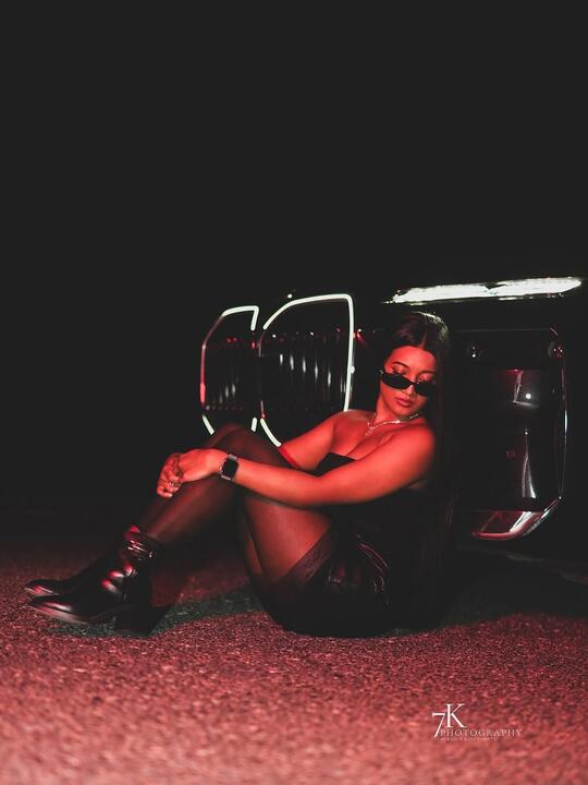 Seated on the ground beside the car, red light