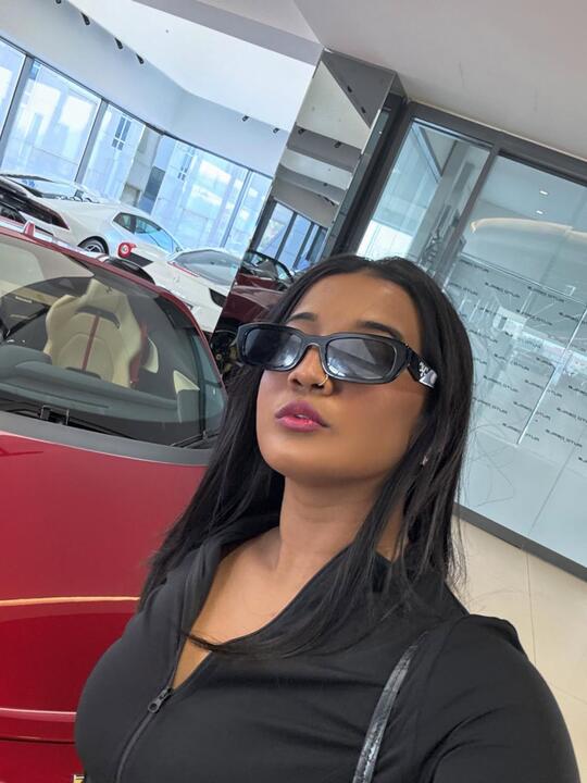 In a showroom beside a red sports car
