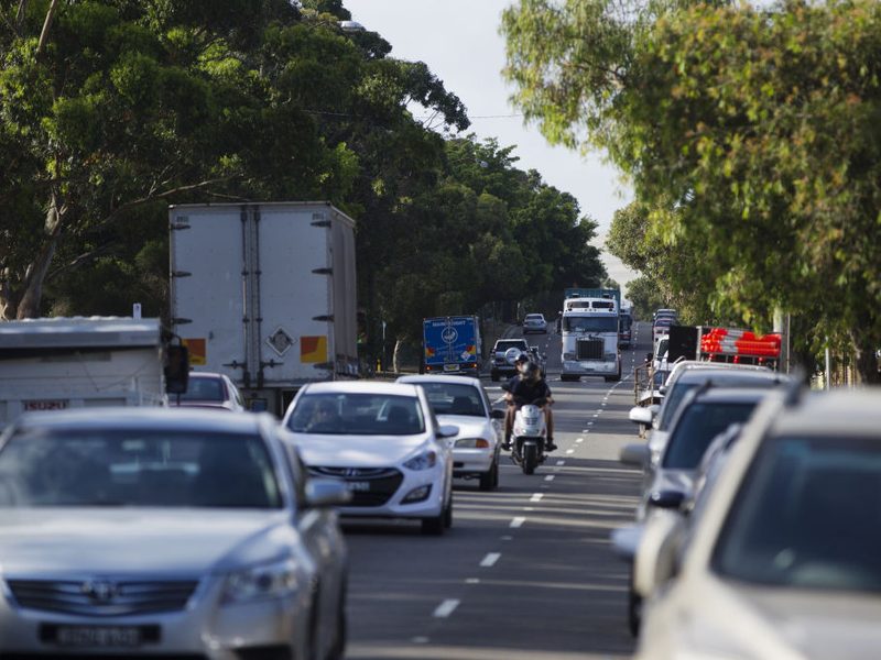 Traffic on a multi-lane suburban road lined with trees