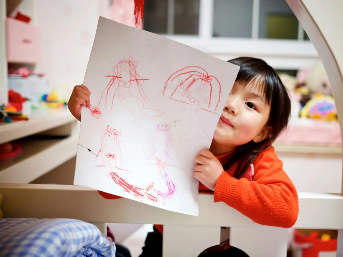 A child proudly holding up a drawing they have made