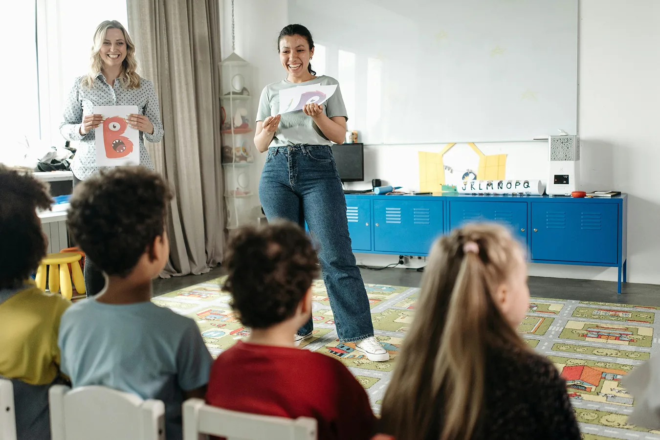 An educator sitting with a small group of children indoors