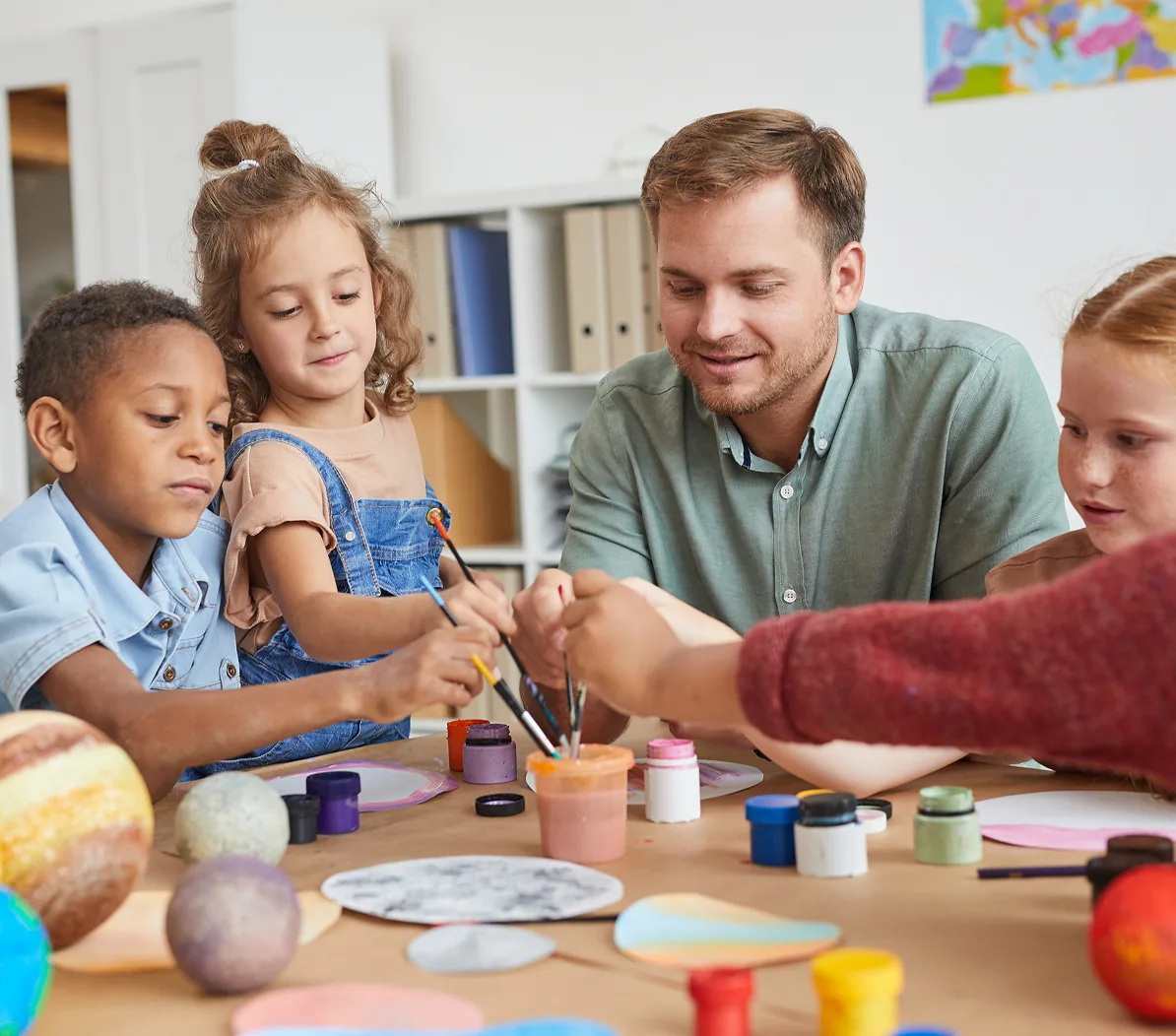 An adult and children painting together at a table