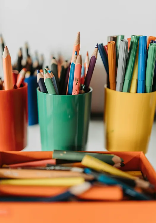 Pots of coloured pencils and crayons on a table