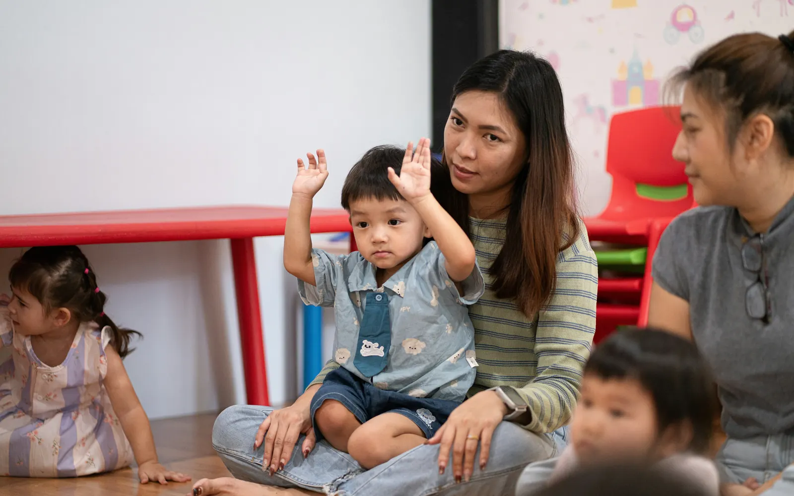 An educator sitting on the floor with a small group of young children during an activity