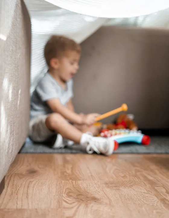 A young child playing quietly on the floor with wooden toys