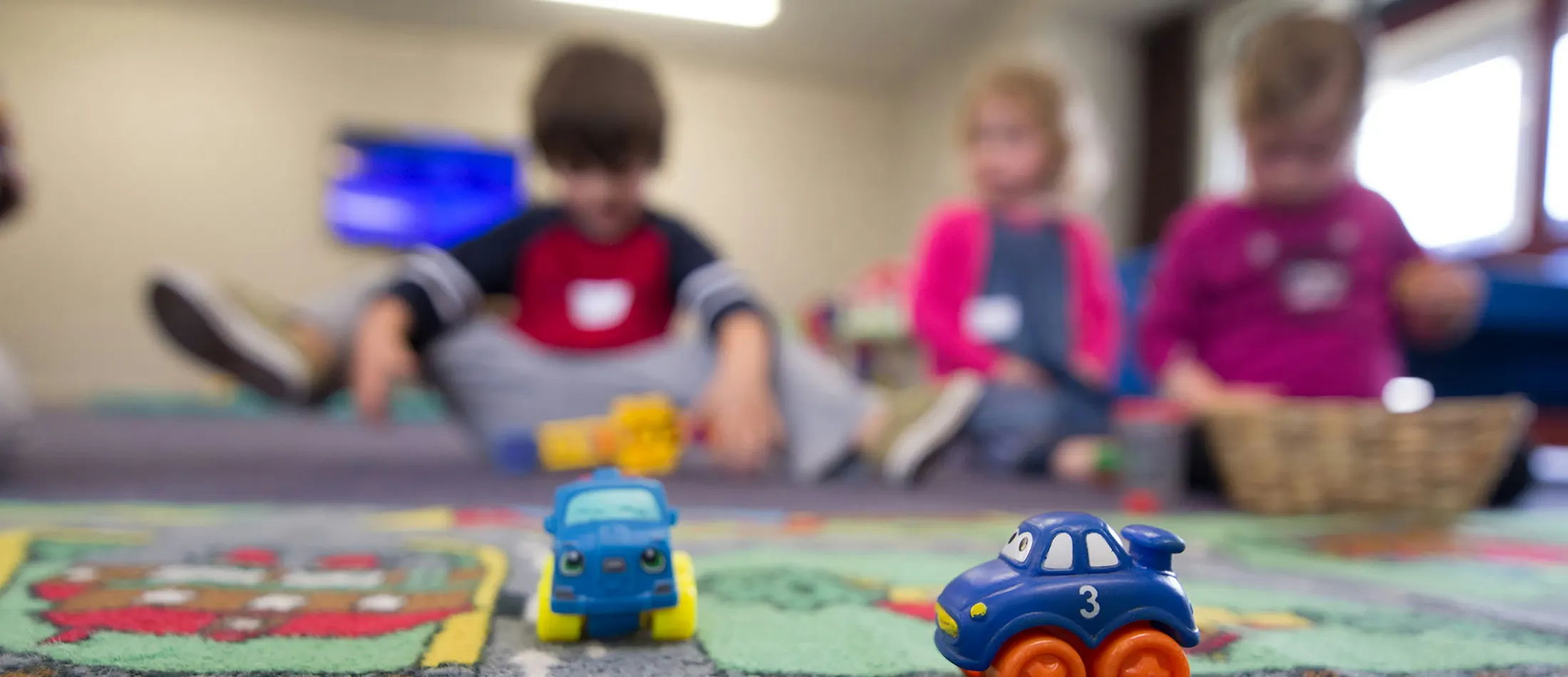 Young children playing together on a rug with wooden toys