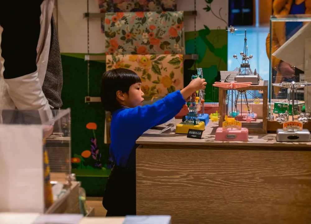 A child reaching across a table while building a model