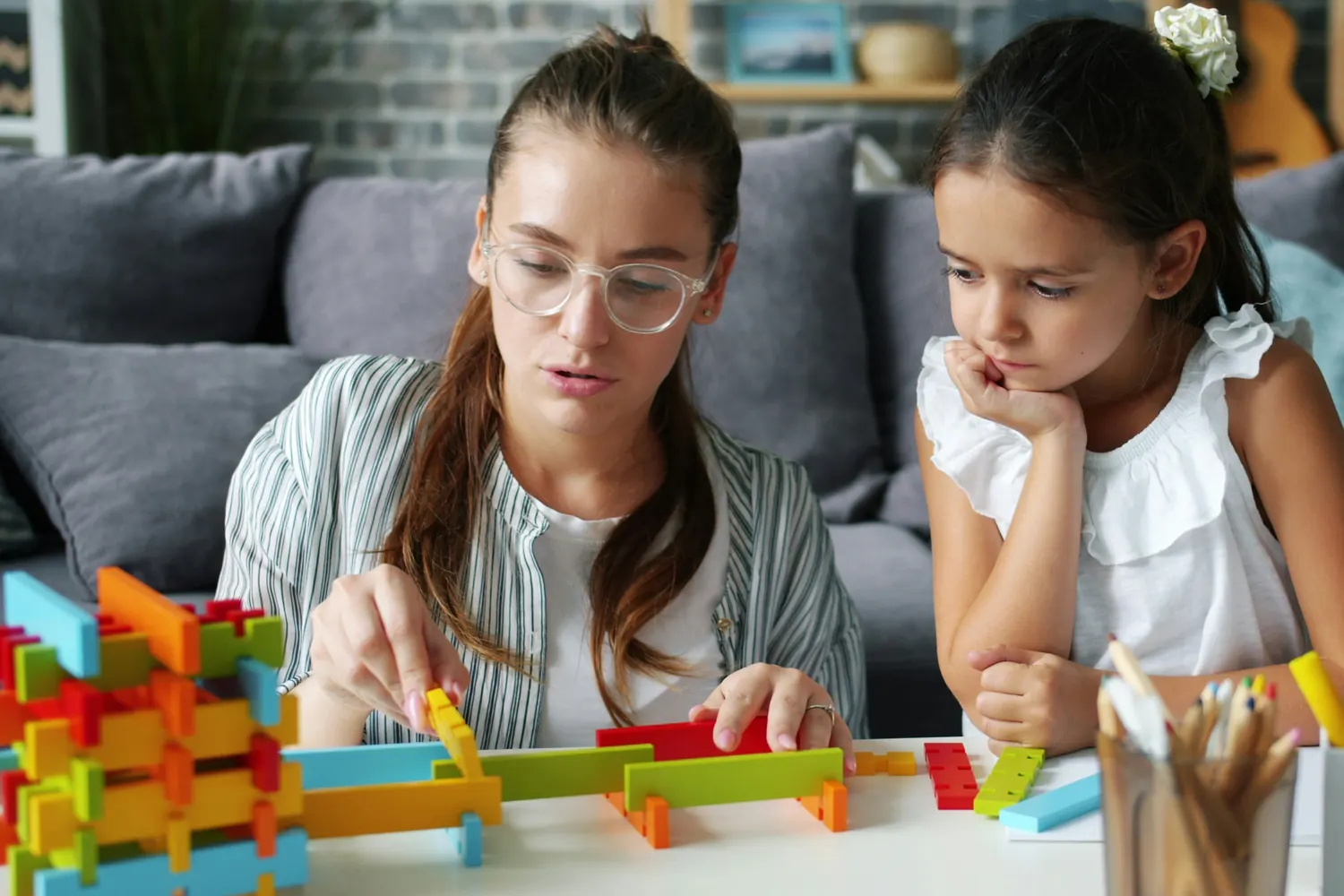 An educator and a child building together with blocks in a home living room