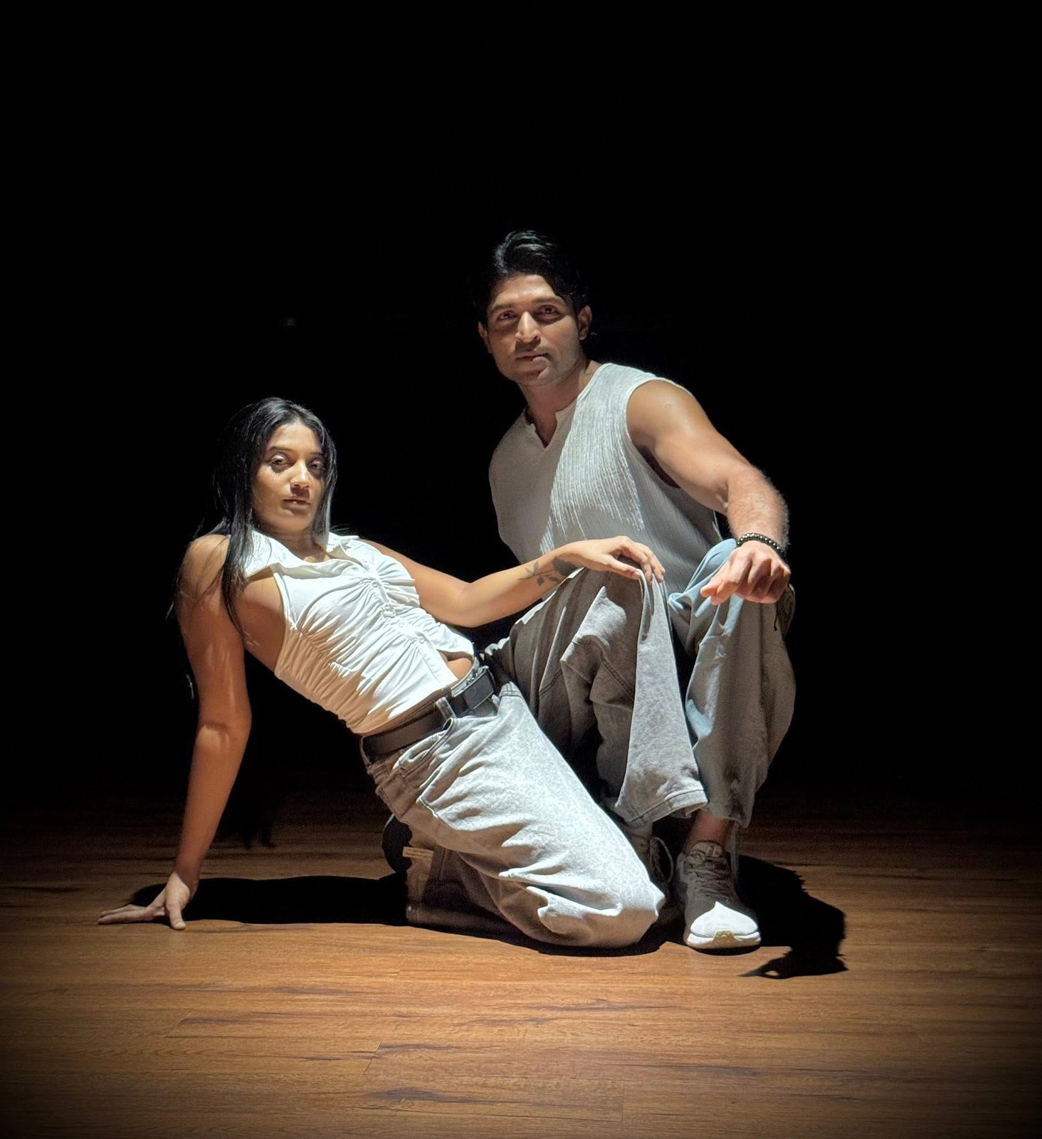 Maneesha and a partner holding a contemporary duet under a single stage light